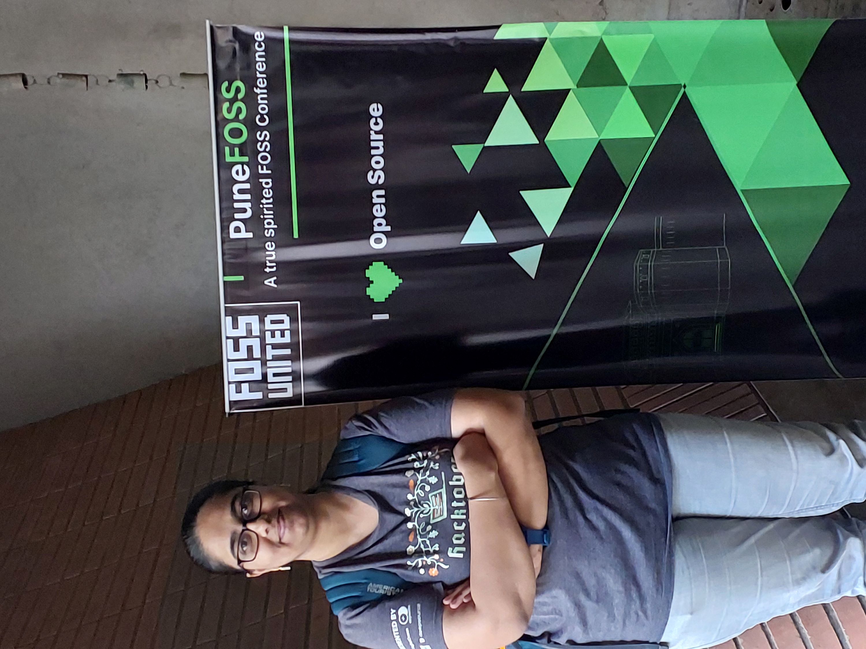 Picture of Jyoti Bhogal, the author of this blog, standing next to the Conference Poster at the PuneFOSS 2.0 event
